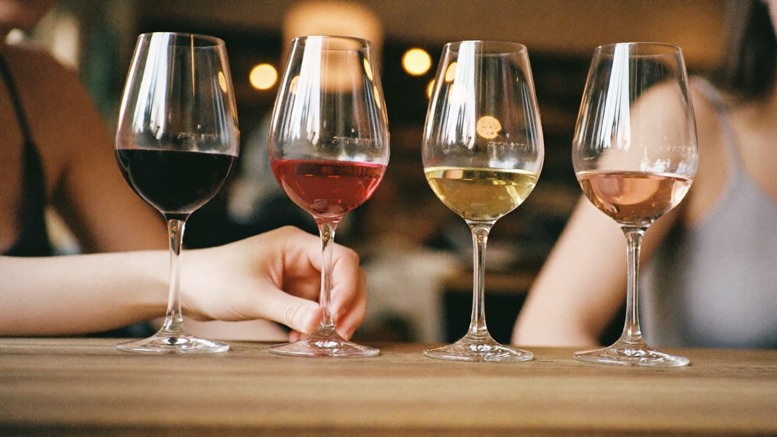 A first tasting flight of red, white and rosé pours with a hand reaching for the nearest glass