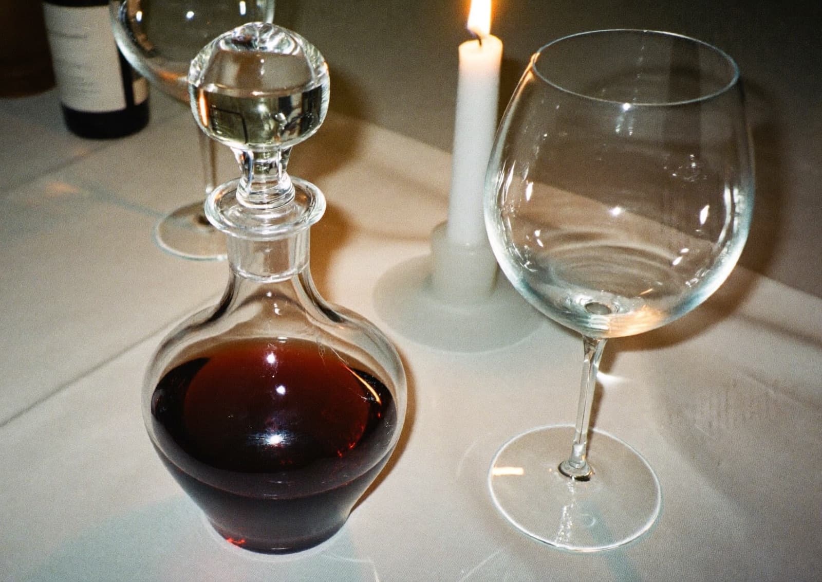 A diner pointing at a wine list while a server nods at a candlelit table