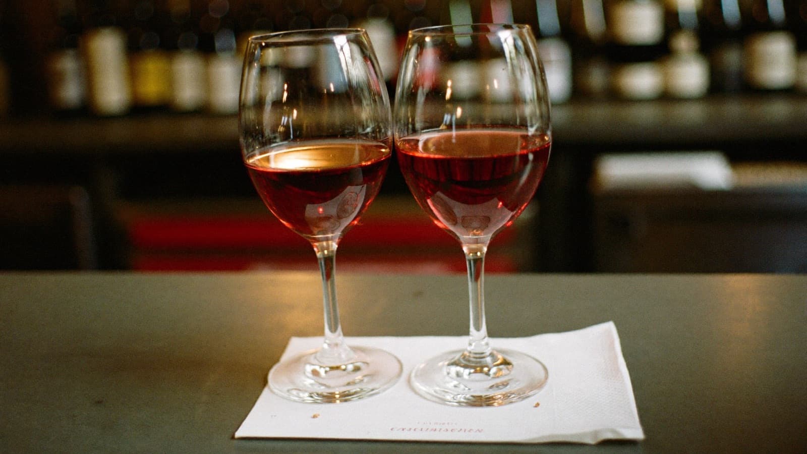 Two identical glasses of red wine side by side on a bar counter for a blind taste-off
