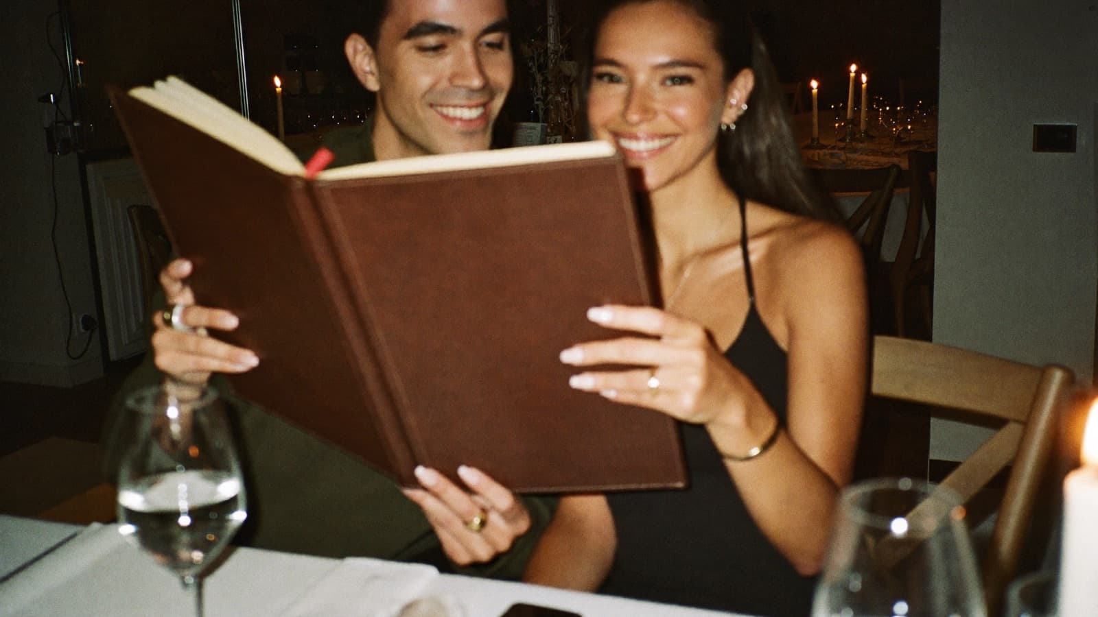 A couple sharing one large wine list by candlelight