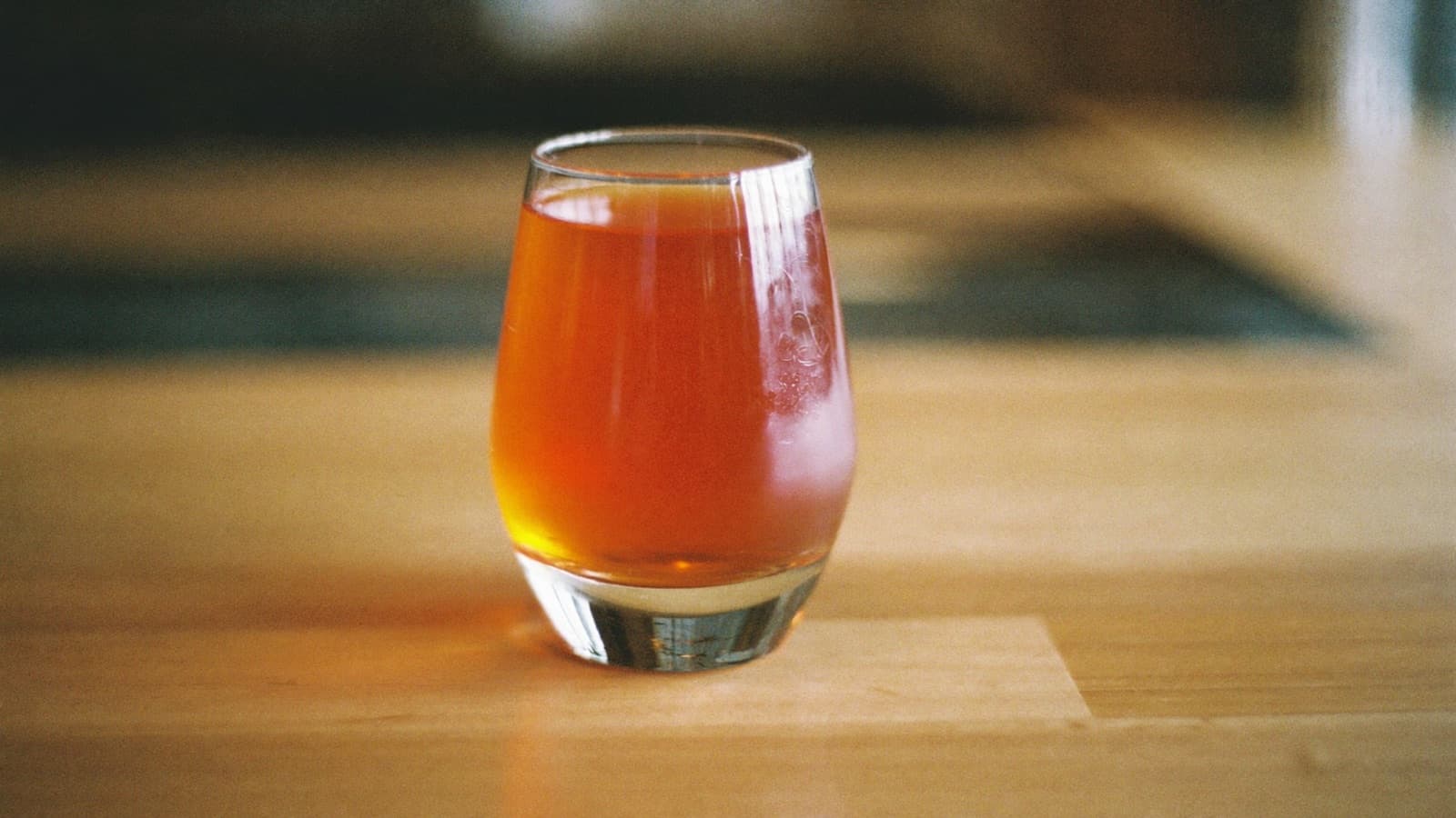 A glass of glowing amber-orange wine on a modern wine bar counter