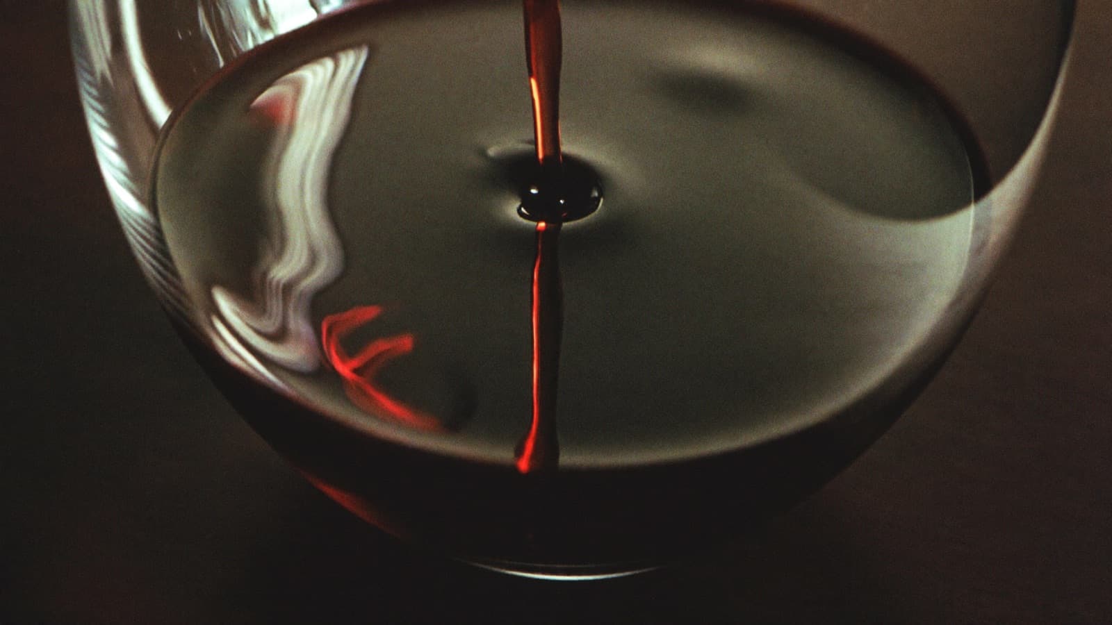 Close-up of red wine legs streaking down the inside of a tilted glass